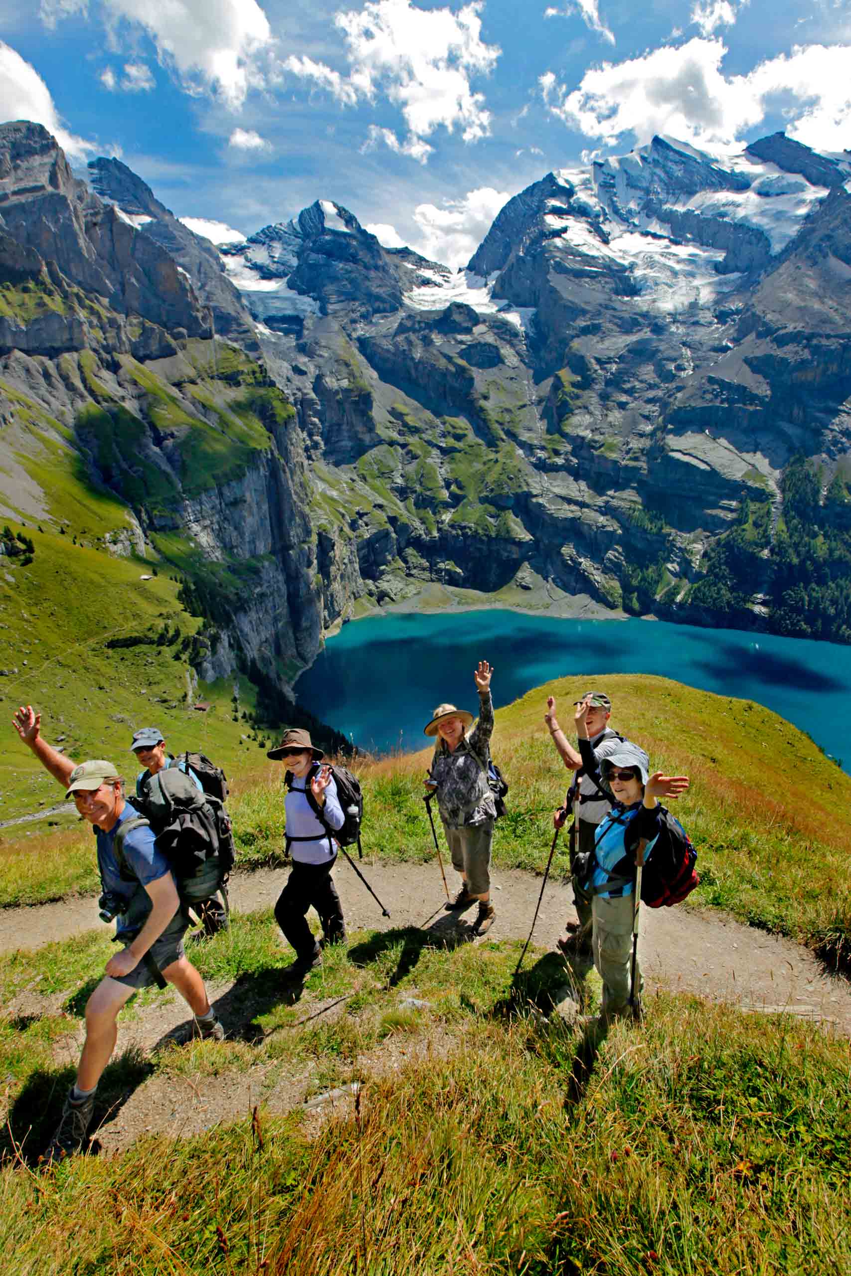 A group of hikers on the Alps with a lake in the background.