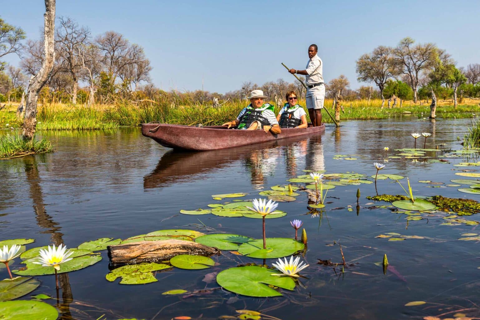 Tourists enjoying a Mokoro ride on the Khwai river in the Okavango Delta, Botswana.