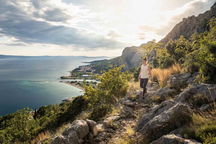A woman walking along a path on cliffs in Croatia.