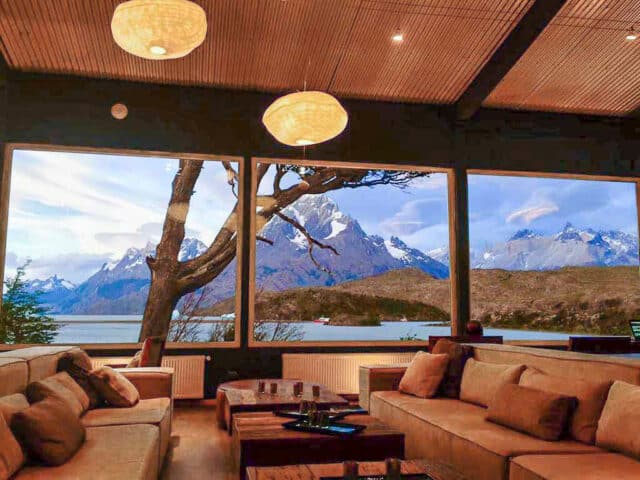 A lounge with large windows that showcase a mountain view in Patagonia.