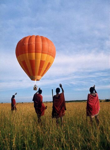 A group of people waving towards a hot air balloon in Tanzania.